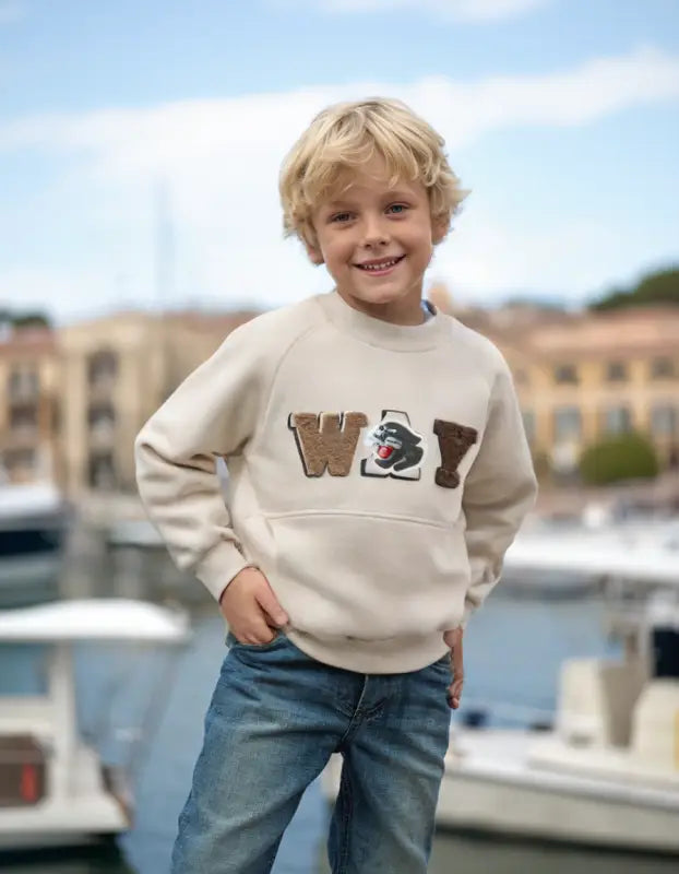 Sweatshirt ve kot pantolonlu gülümseyen çocuk.