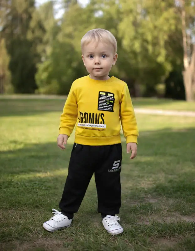 Sarı sweatshirt ve siyah pantolon giyen yürümeye başlayan çocuk.