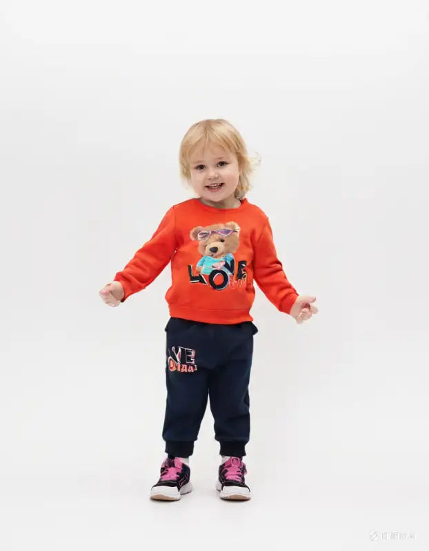 Çocuk turuncu sweatshirt ve mavi pantolon takımı.